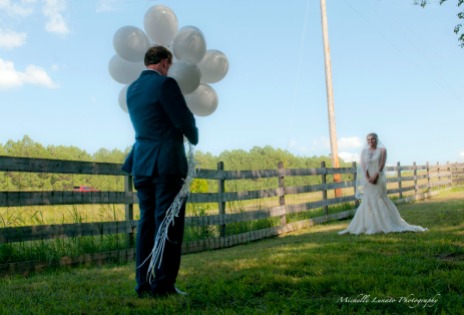 The groom has his face sheilded by ballons and has his eyes closed.